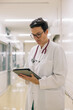 © Amparo Garcia - Woman doctor using digital tablet in hospital corridor for patient care and medical data