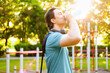© Kyrylo - Thirsty man drinking water from a bottle after an outdoor fitness workout. Proper hydration during sport training at a summer calisthenics park.