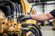 © Snide12 - Mechanic's gloved hand adjusting hydraulic lines on heavy construction machinery