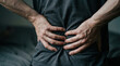 © INT888 - Person back pain hand lower waist massage injury muscle health adult holding lower back with both hand, showing discomfort and strain, indoor close up medical concept