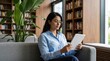 © 5 Grace Media - Young Woman Reading Ebook on Digital Tablet in Modern Library.