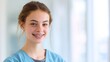 © Prapan - Young Woman with Braces and Blue Scrubs: A close-up portrait of a young woman, possibly a medical student or professional, wearing blue scrubs and visible dental braces, smiling warmly.