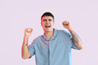 © Pixel-Shot - Excited young man celebrating success with fists raised and eyes closed, expressing joy and achievement