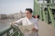 © Cavan Images - Smiling Asian man reads newspaper on a city bridge