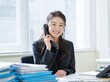 © Jumpei - オフィスで笑顔の日本人女性が電話応対する明るい職場で働くビジネスパーソン