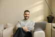 © Mihajlo Ckovric/Stocksy - Man Sitting on Sofa With Laptop in Bright Room During Day Smiling