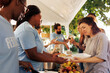 © DC Studio - Hunger relief team of volunteers donates essential items and free food to needy, showing generosity in serving less fortunate. Non-profit outdoor food bank sharing warm meals to poor homeless people.