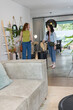 © wavebreak3 - Diverse female travelers standing and talking in bright modern living dining area with suitcases
