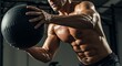 © MakarimZaydan - Pessoa musculosa se exercitando com uma bola medicinal em uma academia.
