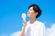 © Susie - ハンディ扇風機を持つ若い男性