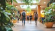 © Ndoomyim - Blurred people walking through a sunlit shopping mall interior decor with green potted plants.
