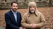 © Iqra - Two mature men stand together outdoors wearing contrasting professional dark navy suit attire and casual beige knitted sweater with matching winter hat during an autumn day with soft natural ambient