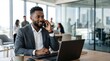 © Eve - Smiling African American businessman talking on mobile phone while working on laptop in modern open space corporate office, young male manager calling client, business communication concept