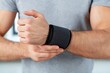 © whitestorm - Man's hand wearing a black wrist support brace for fitness and injury prevention, close-up.
