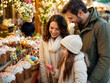 © superstock - Familie entdeckt russische Ostergebäcke und bunte Eier an einem festlichen Marktstand