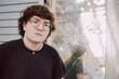 © Luciano Spinelli/Stocksy - Young Man Poses in Front of Broken Window