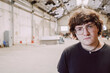 © Luciano Spinelli/Stocksy - Young Man Stands Confidently in an Empty Industrial Space