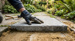 © Mahmuda - laying paving slabs in garden | DIY patio installation project | professional landscaping stone work | gloved hand pressing concrete paver