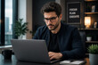 © mila103 - Man focused typing on laptop at modern office desk