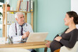 © JackF - Pregnant woman expresses her complaints to an elderly male doctor sitting in front of a laptop