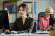 © DragonImages - Medium shot of Asian young adult woman wearing headset, typing at computer in call center office, handling customer support and teamwork. Ideal for service business and CRM marketing