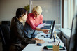 © DragonImages - Young adult Asian woman working at call center desk while middle aged Caucasian woman guiding on computer, showing customer support teamwork. For service training, CRM, outsourcing marketing