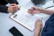 © Apichat - Business Meeting with Person Reviewing Resume and Taking Notes at Desk