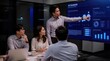 © Syafiq Rahman - Diverse group of business professionals collaborating around a large interactive screen displaying intricate AI analysis charts and graphs, presenting data-driven insights in a dynamic office