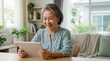 © OlgaNeuroArt - Asian senior woman using a tablet computer at home. Happy elderly female on a video call or telemedicine consultation. Technology for seniors concept