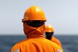 © Larisa - Workers in orange safety gear observe vast ocean, showcasing tea