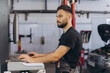 © anatoliycherkas - Auto technician performing digital car diagnostics on a monitor, checking vehicle systems in a modern professional workshop