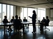 © Yurgentum - Silhouetted professionals gather for a meeting in a modern office setting.