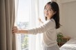 © AiPhoto - カーテンを開ける朝の白い服の女性