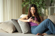 © PheelingsMedia - Happy young woman using smart phone checking online content