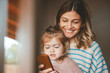 © Westend61 - Smiling young woman showing mobile phone to daughter seen through window