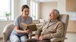 © Iuliia - Nurse reading book to senior man in nursing home. Caregiver providing companionship and support to elderly male patient. Healthcare assistance and wellness in assisted living facility.