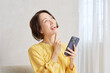 © siro46 - リビングでスマートフォンを使う女性　想像する
