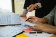 © Witoon - Business professionals reviewing financial reports and performance charts at a meeting table, discussing data insights and strategy with a laptop in a modern office.