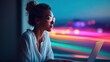 © Glitchmint - Focused woman in glasses working on laptop at night with blurred city lights in background