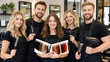 © Yuliia Yevdokymova - Group portrait of smiling Caucasian hairdressers standing in modern beauty salon holding professional