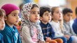 © shobakhul - Group of young children sit together listening attentively in a classroom setting.