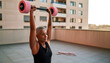 © Larisa - Elderly woman exercising with dumbbells on balcony during sunset