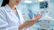 © Vicentia - A female doctor holding a modern hearing aid device in her open hands, showing innovative medical technology for hearing loss treatment inside a clinical hospital room.