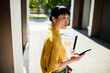 © Davor - Businesswoman checking smartphone outside office building