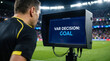 © Hiskia - Over the shoulder view of a professional soccer referee checking the video assistant referee monitor for a goal decision in a large stadium