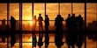 © hajime - Silhouettes of people in office against sunset cityscape