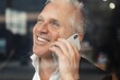 © Rawpixel.com - Smiling man talking on a smartphone, wearing a white shirt, indoors.