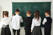 © Pixel-Shot - Cute little pupils drawing on blackboard in classroom, back view. School holidays concept