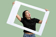 © Pixel-Shot - Beautiful shocked young woman with frame on green background