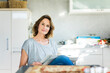 © Westend61 - Portrait of woman with newspaper in kitchen at home
